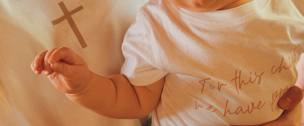 A baby held close, in a Bee and Lion tee