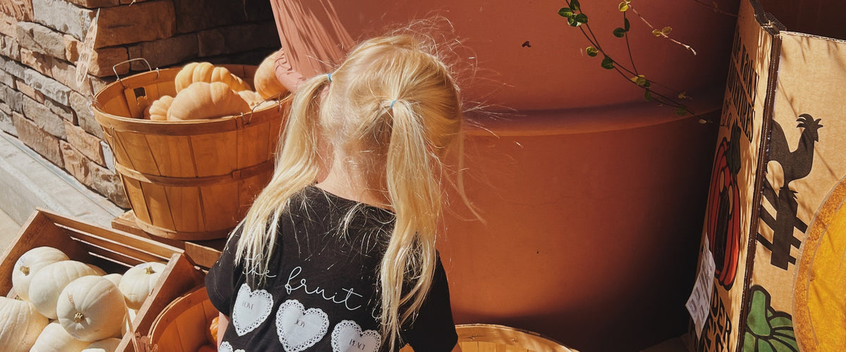 A toddler in a Bee and Lion tee at the pumpkin patch